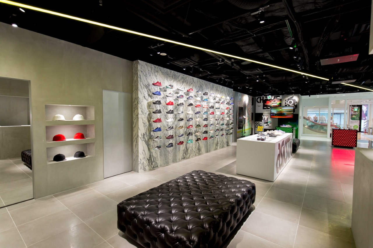 ASICS Tiger store interior with marble shoe display wall and leather seating